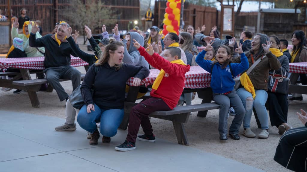 Group of students at picnic table cheer in unison