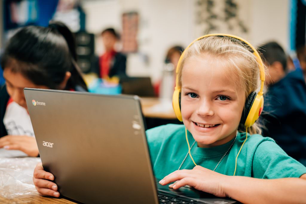 Student with headphones receiving tutoring on a laptop.